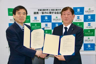 協定式で握手を交わす村上雅人学長(左)と西村泰志学長(右)