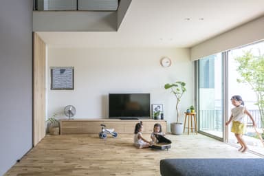 屋外のウッドデッキからフラットにつながる開放的なリビングで走り回る子どもたち