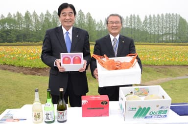 互いの特産品を手にする肥後 正弘・小林市長(右)と持木 一茂・能登町長(左)